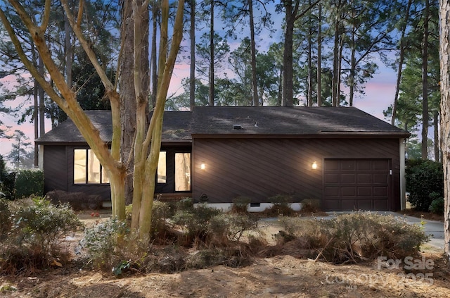 exterior space with an attached garage and a shingled roof