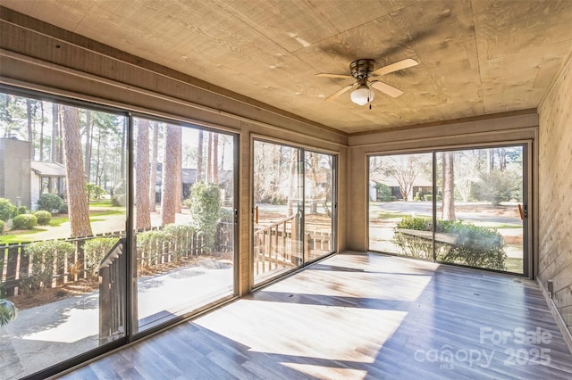 unfurnished sunroom featuring a wealth of natural light, wood ceiling, and a ceiling fan