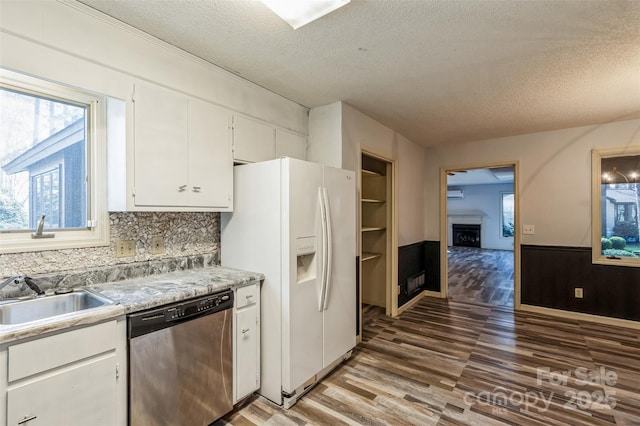 kitchen featuring white cabinetry, light wood-style flooring, a sink, white refrigerator with ice dispenser, and stainless steel dishwasher