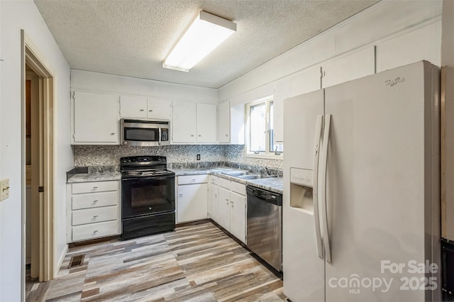 kitchen with light wood finished floors, backsplash, appliances with stainless steel finishes, white cabinets, and a sink