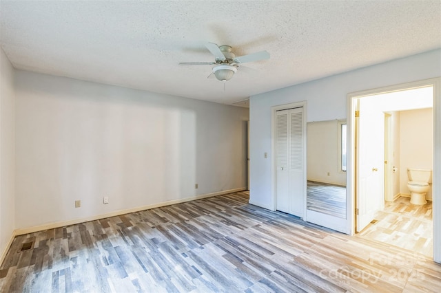 unfurnished bedroom featuring baseboards, light wood-style floors, a closet, and a textured ceiling