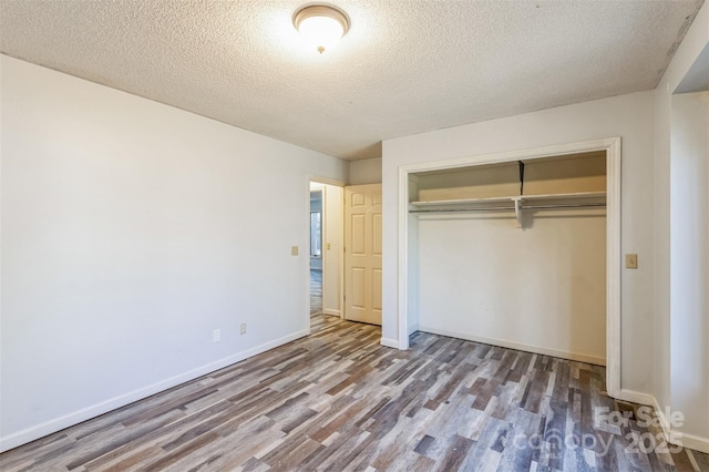 unfurnished bedroom with a closet, baseboards, and wood finished floors