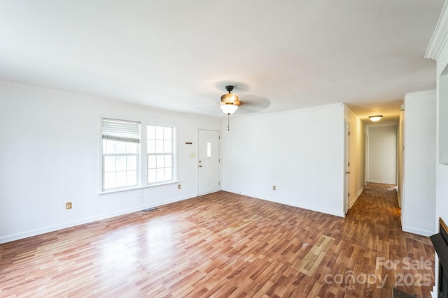 empty room with visible vents, crown molding, baseboards, light wood-style floors, and a ceiling fan