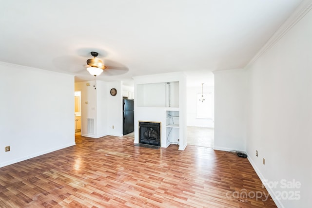 unfurnished living room with a fireplace with flush hearth, ornamental molding, a ceiling fan, light wood finished floors, and baseboards