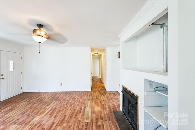 unfurnished living room featuring baseboards, a fireplace, ornamental molding, ceiling fan, and light wood-style floors