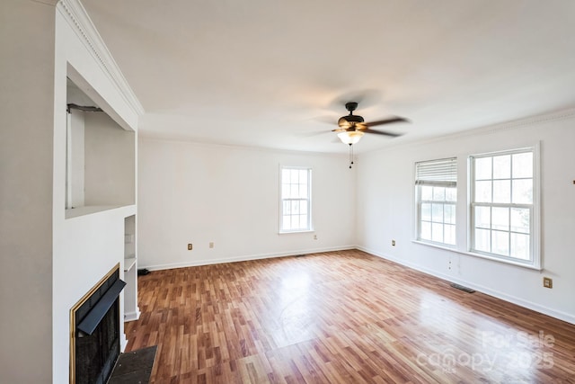 unfurnished living room with wood finished floors, a ceiling fan, visible vents, baseboards, and a fireplace