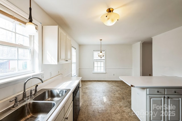 kitchen with pendant lighting, a sink, black dishwasher, light countertops, and baseboards