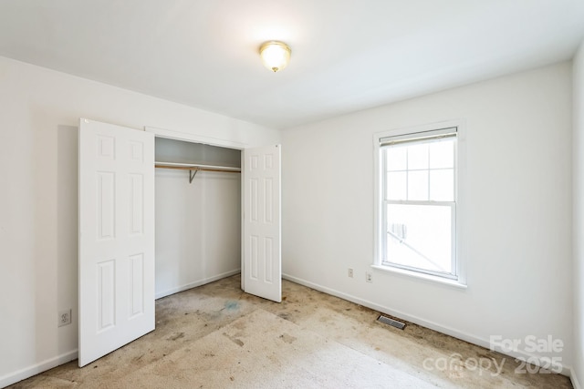 unfurnished bedroom with visible vents, baseboards, carpet floors, and a closet