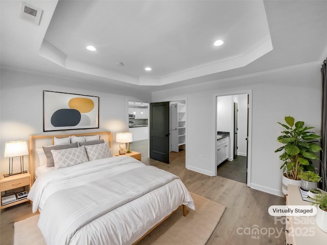 bedroom with wood finished floors, visible vents, recessed lighting, a walk in closet, and a raised ceiling