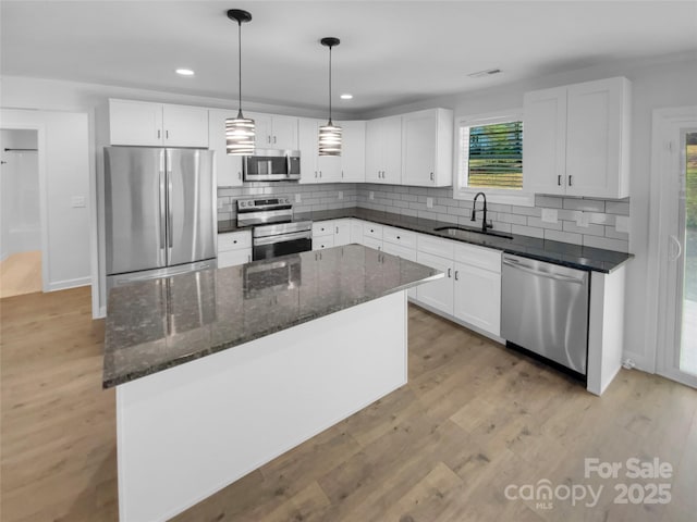 kitchen featuring light wood finished floors, white cabinets, stainless steel appliances, and a sink