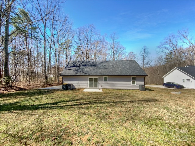 rear view of property with central air condition unit, a lawn, and a shingled roof