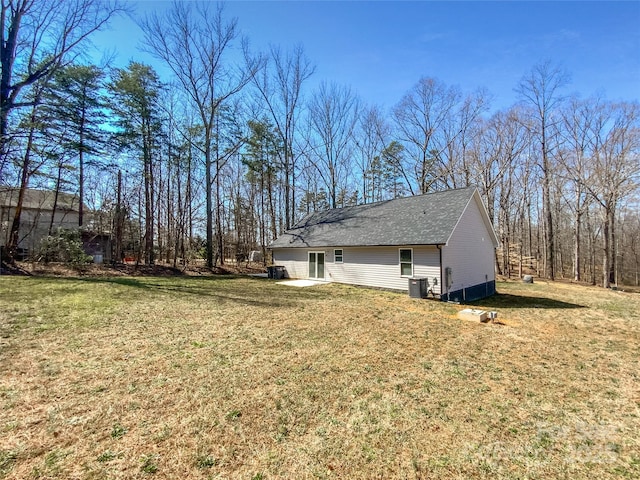 view of property exterior with a lawn, central AC, and roof with shingles