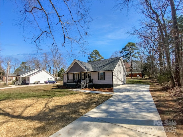 view of front of home with covered porch, concrete driveway, and a front yard