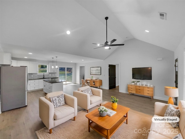 living room with a ceiling fan, visible vents, light wood finished floors, recessed lighting, and vaulted ceiling