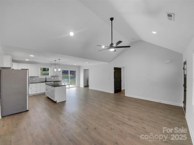 unfurnished living room featuring baseboards, wood finished floors, visible vents, and ceiling fan