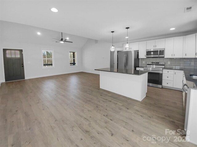 kitchen with visible vents, backsplash, dark countertops, wood finished floors, and appliances with stainless steel finishes