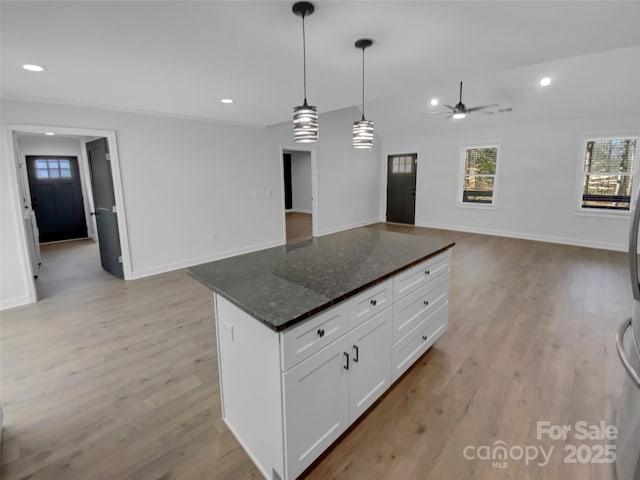 kitchen featuring light wood-style floors, white cabinets, a ceiling fan, and open floor plan