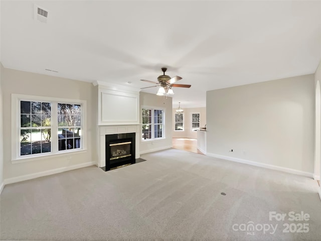 unfurnished living room featuring visible vents, a fireplace with flush hearth, baseboards, light colored carpet, and ceiling fan