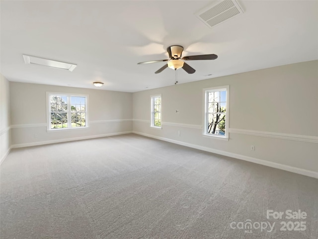 carpeted empty room featuring a wealth of natural light, visible vents, baseboards, and attic access