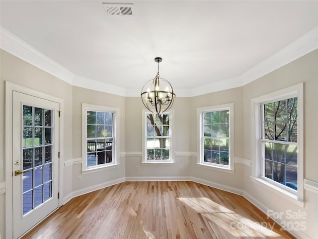 unfurnished dining area featuring visible vents, a notable chandelier, light wood-style floors, crown molding, and baseboards