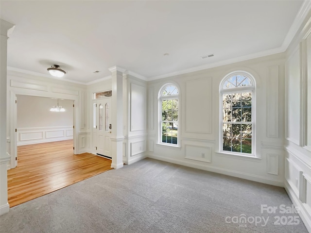 empty room featuring crown molding, a decorative wall, a notable chandelier, and visible vents