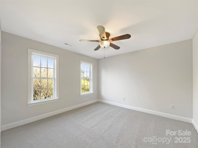 carpeted empty room featuring visible vents, baseboards, and a ceiling fan