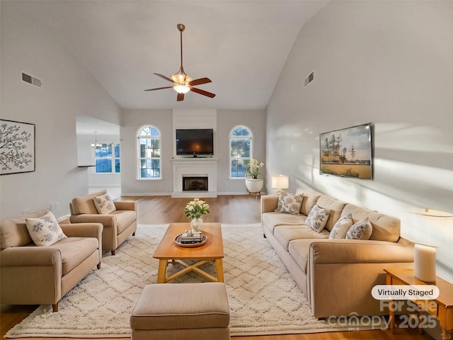 living area with visible vents, wood finished floors, high vaulted ceiling, and ceiling fan