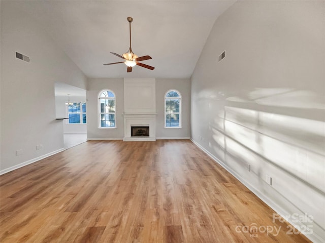 unfurnished living room featuring light wood-type flooring, visible vents, a fireplace with raised hearth, and ceiling fan