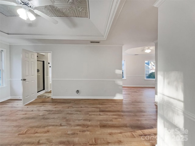 empty room with crown molding, wood finished floors, visible vents, and ceiling fan