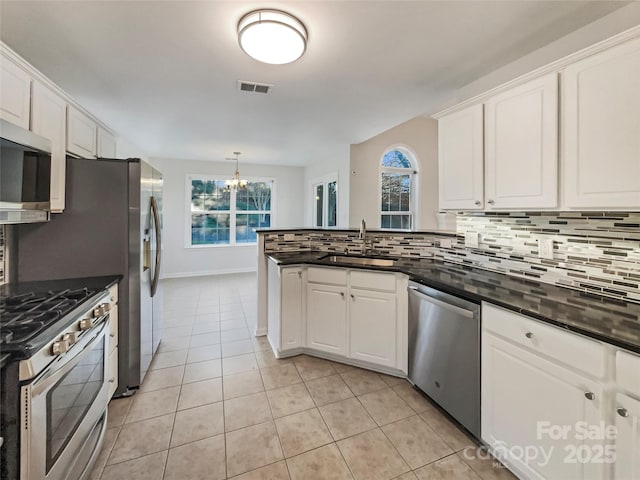 kitchen featuring visible vents, backsplash, appliances with stainless steel finishes, an inviting chandelier, and a sink