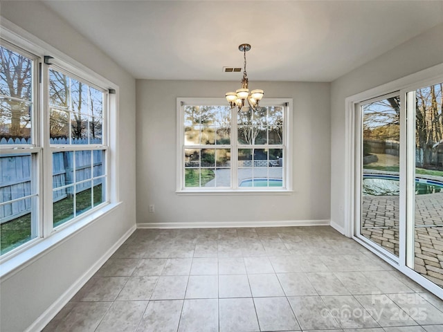 unfurnished dining area with a wealth of natural light, baseboards, and an inviting chandelier