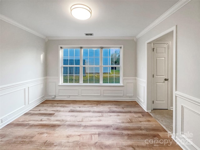 empty room with crown molding, wood finished floors, and visible vents