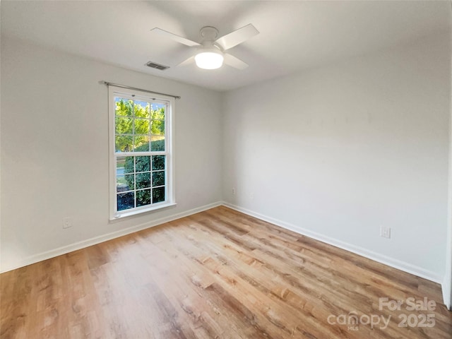 empty room featuring baseboards, wood finished floors, visible vents, and ceiling fan