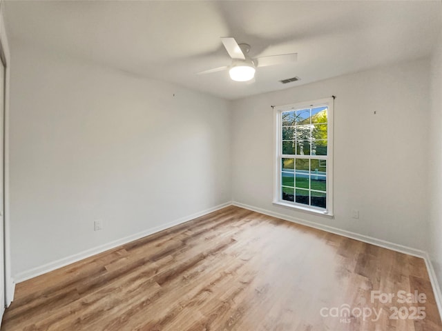 spare room featuring visible vents, baseboards, ceiling fan, and wood finished floors