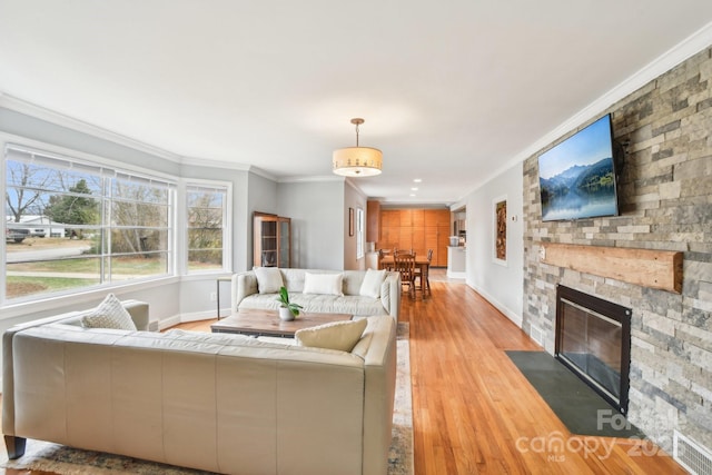 living room featuring a fireplace, wood finished floors, baseboards, and ornamental molding