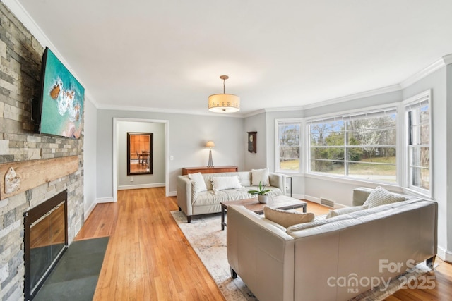 living room featuring a stone fireplace, crown molding, and wood finished floors