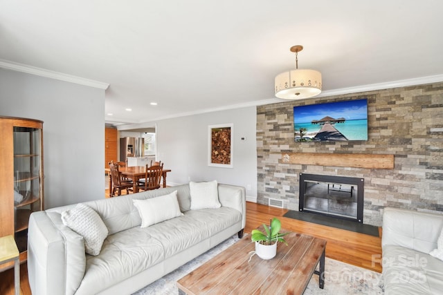 living room with wood finished floors, baseboards, a fireplace, recessed lighting, and ornamental molding