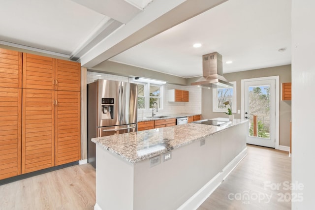 kitchen with light wood-style flooring, island exhaust hood, stainless steel fridge, black electric stovetop, and light stone countertops