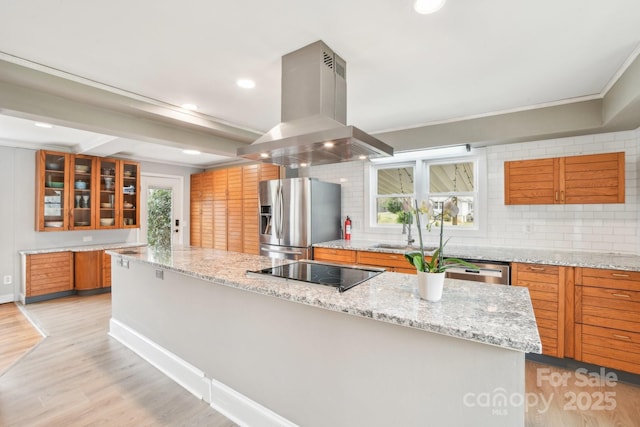 kitchen with black electric stovetop, stainless steel fridge with ice dispenser, light wood-type flooring, brown cabinets, and island exhaust hood