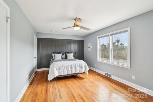 bedroom featuring ceiling fan, light wood-style floors, visible vents, and baseboards