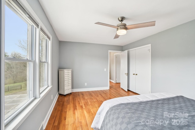 bedroom with ceiling fan, baseboards, a closet, and light wood-type flooring