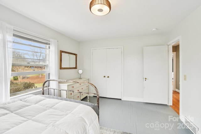 bedroom with wood finished floors, a closet, and baseboards