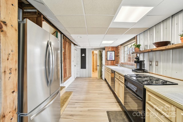 kitchen featuring light wood finished floors, open shelves, a drop ceiling, stainless steel appliances, and a sink