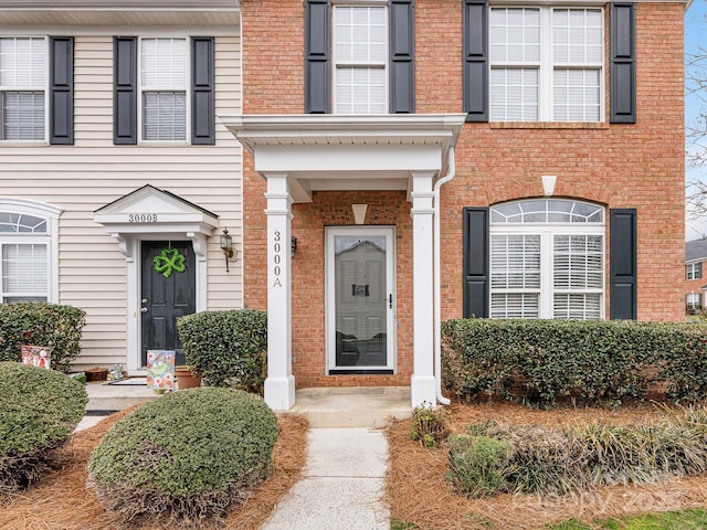 view of exterior entry featuring brick siding