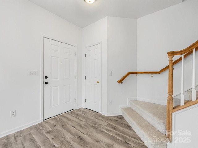 entrance foyer with baseboards, wood finished floors, and stairs