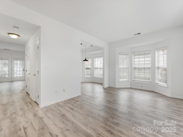 unfurnished living room with light wood-type flooring, visible vents, and baseboards