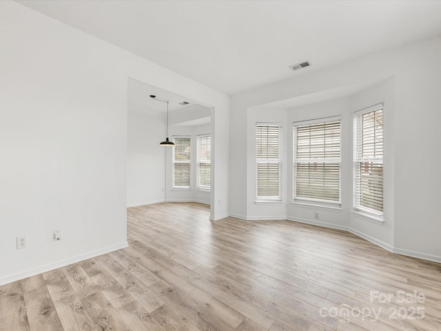 unfurnished room featuring visible vents, light wood-style flooring, and baseboards