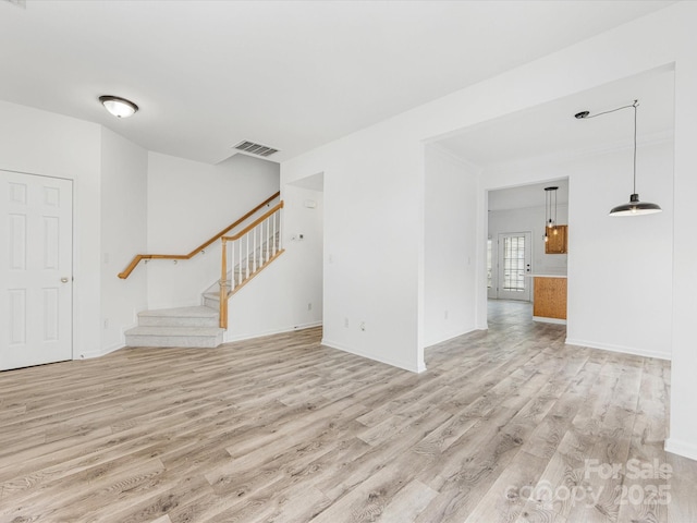 unfurnished living room featuring stairway, baseboards, visible vents, and wood finished floors