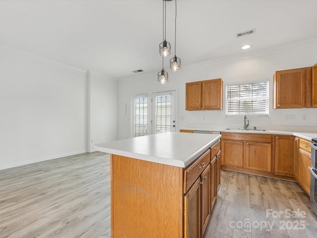 kitchen featuring visible vents, ornamental molding, light wood-style floors, and a sink