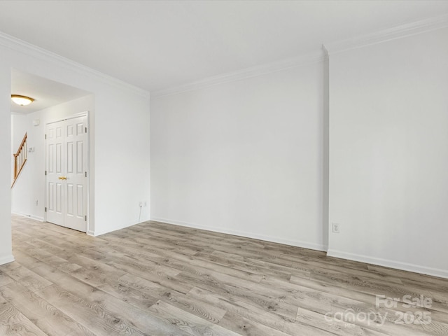 empty room with crown molding, baseboards, and wood finished floors